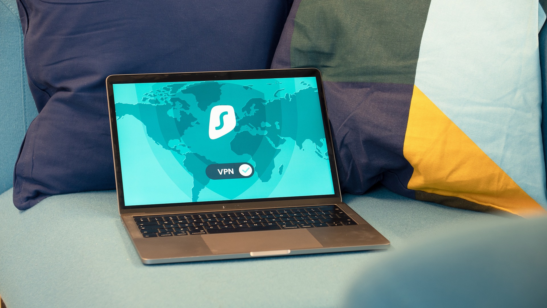 Sofaecke mit Kissen. Auf dem Kissen ist ein eingeschalteter Laptop. Auf dem Laptop läuft eine generische VPN-App. Der VPN-Tunnel ist aktiv.
