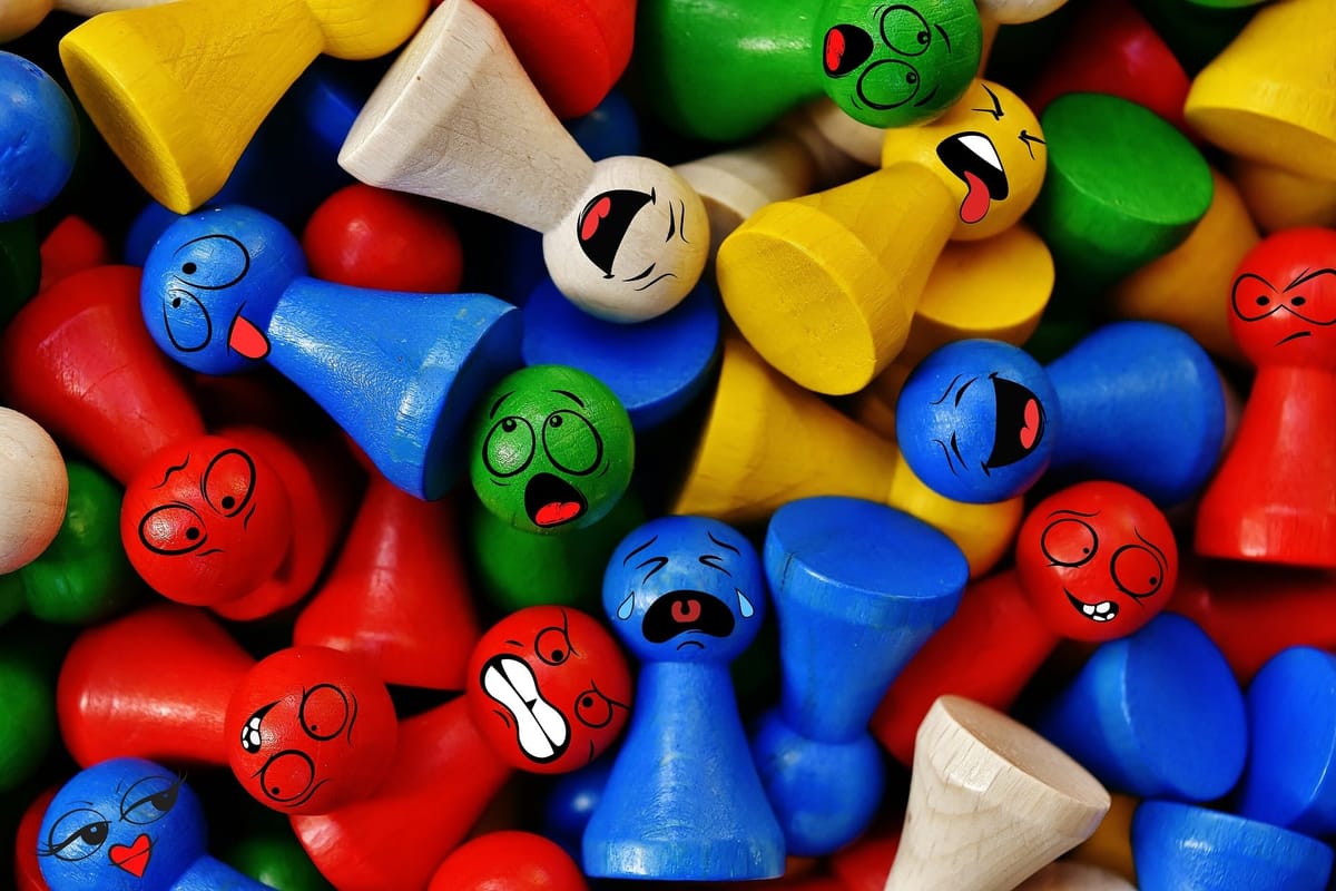 Das Bild zeigt viele bunte Spielsteine; eine Community. Die meisten Holzfiguren sind ohne Gesicht, doch ein paar haben eine M